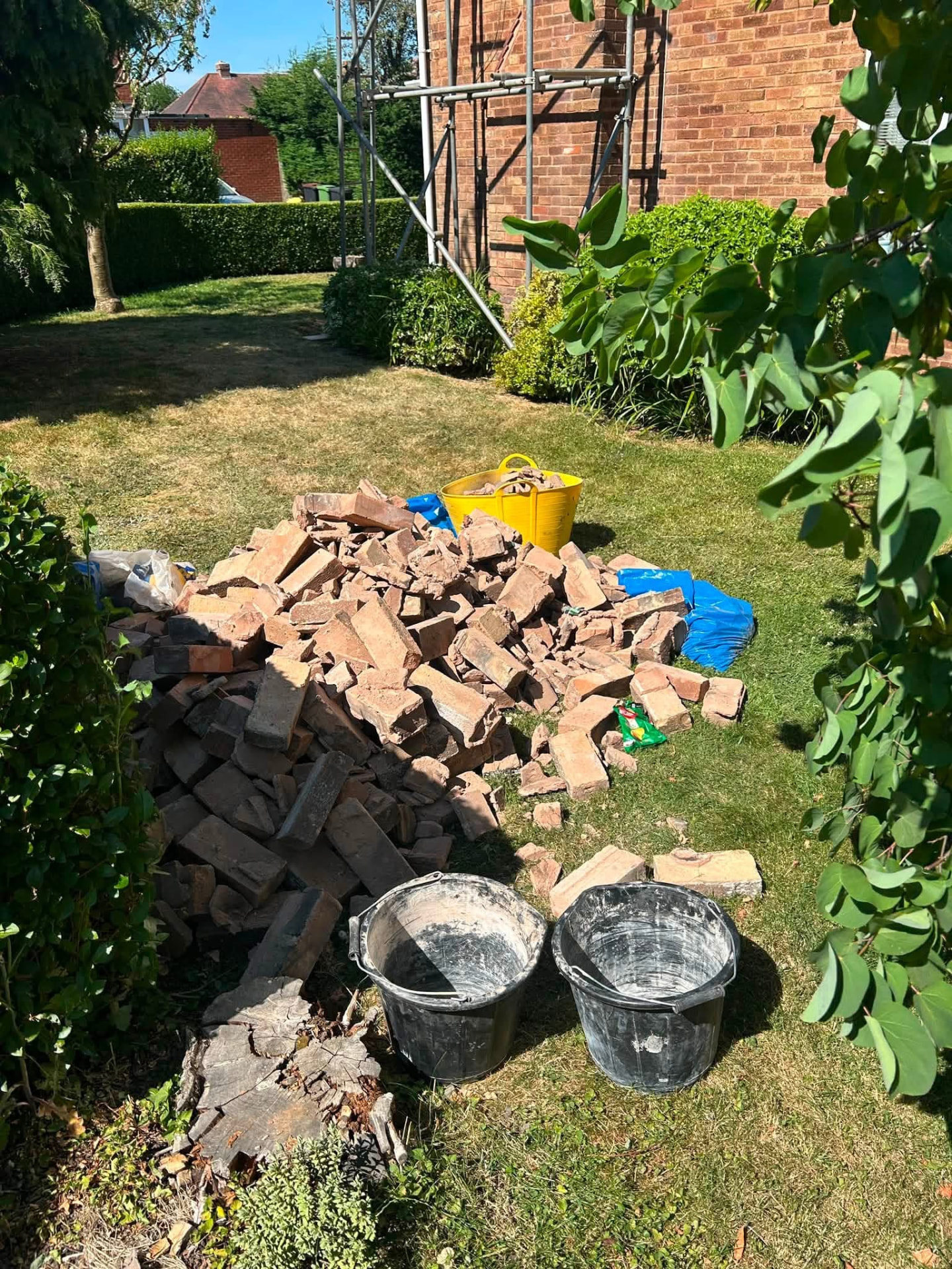 Bricks and garden waste piled on a lawn, ready for collection by Newys Removals