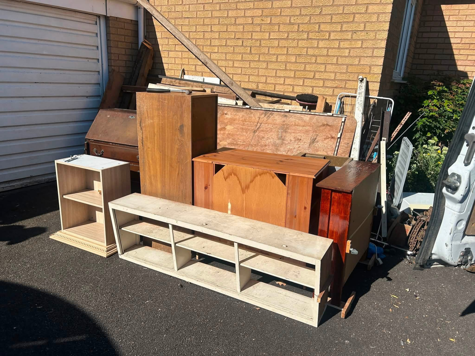 Old furniture, shelving and timber stacked on a driveway ready for waste clearance in the West Midlands