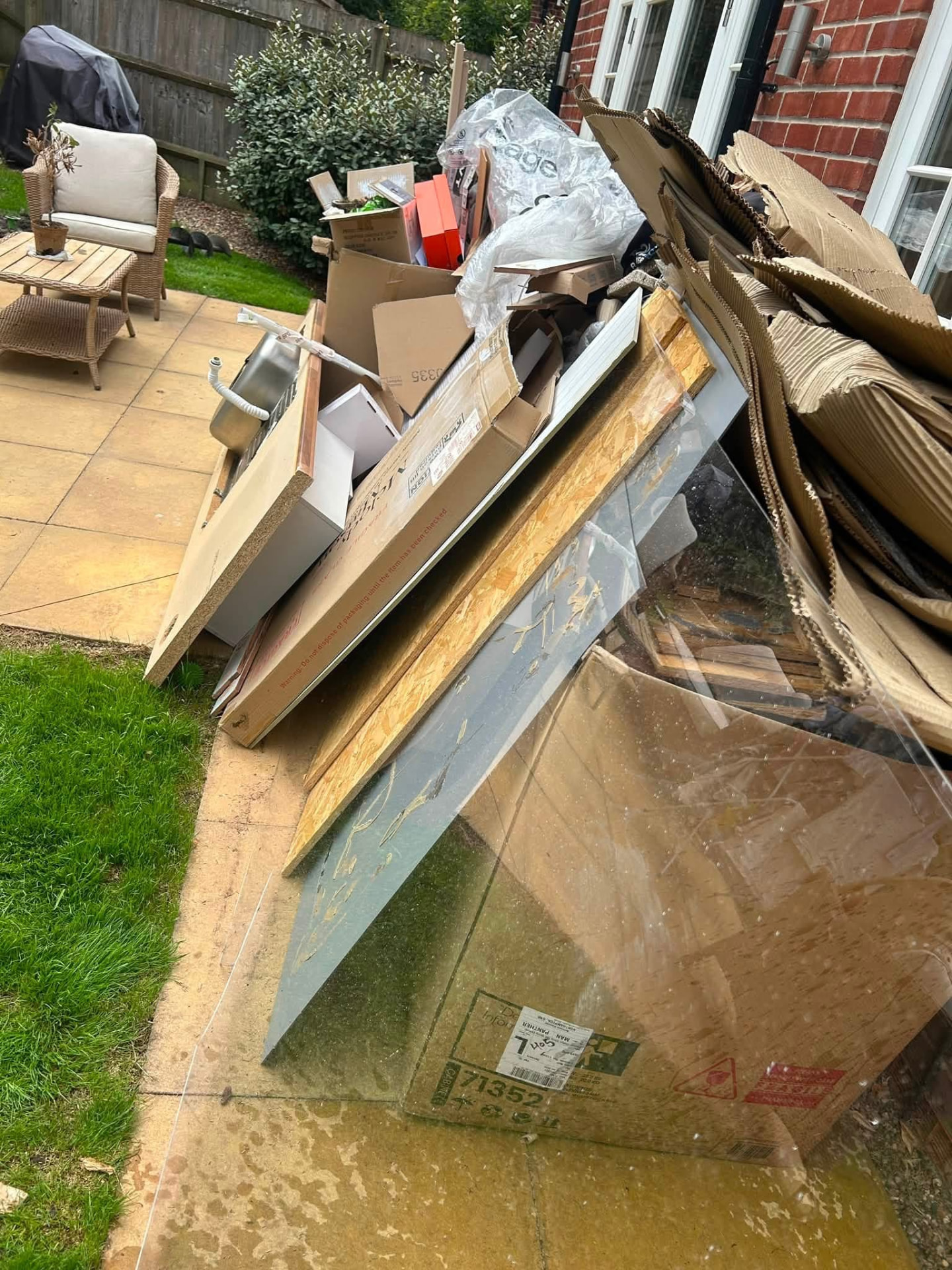Garden waste, boards and glass panels piled on a patio ready for rubbish removal in Worcestershire
